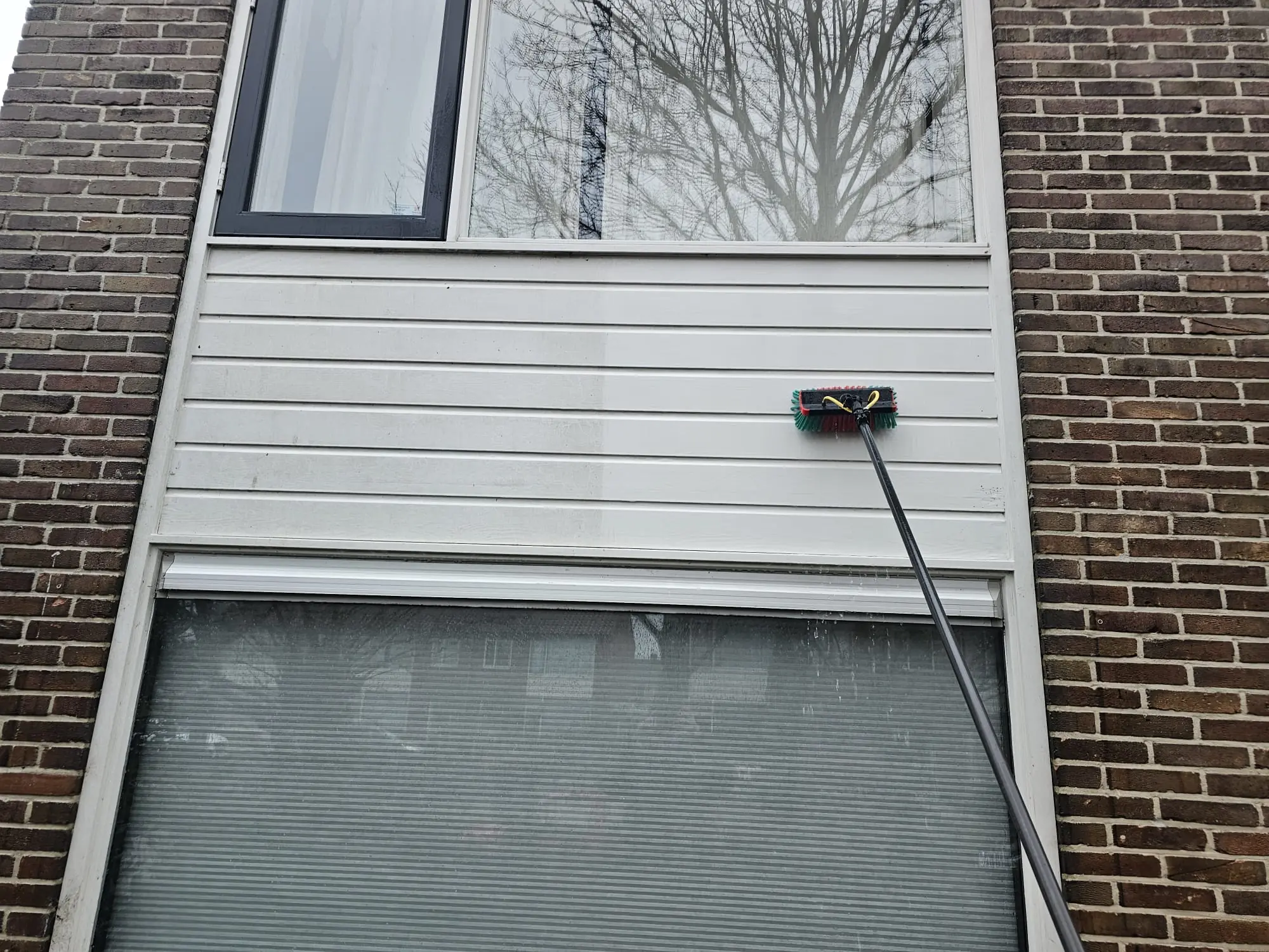 Kings Cleaning reinigt kunststof gevelbekleding met een telescoopborstel